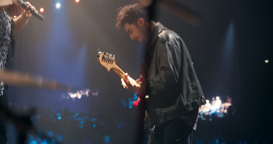 Rock Music Concert at a Festival: Energetic Indie Guitarist Performs Live on Stage, Using Electric Guitar to Play Indie, Punk, and Alternative Tunes. Multiethnic Man Enjoying the Music
