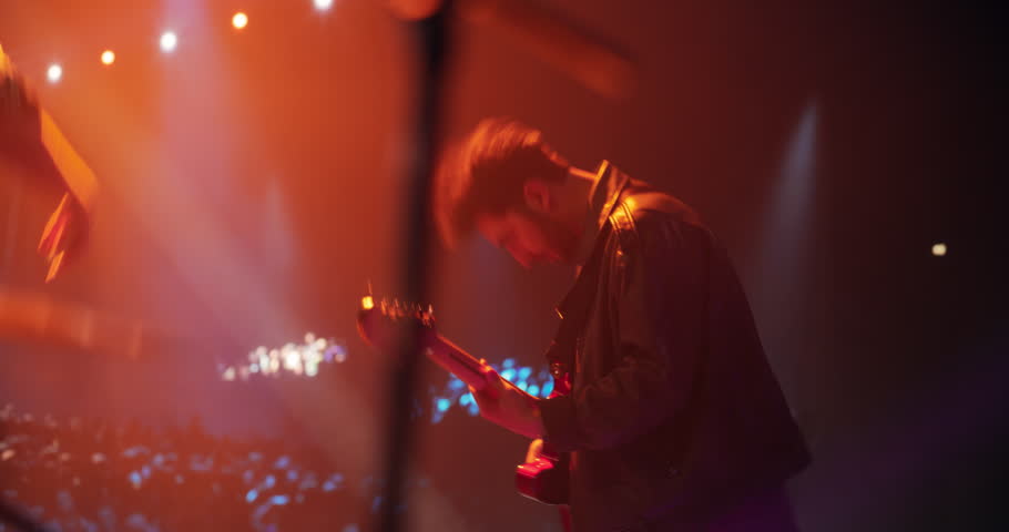 Rock Music Concert at a Festival: Energetic Indie Guitarist Performs Live on Stage, Using Electric Guitar to Play Indie, Punk, and Alternative Tunes. Multiethnic Man Enjoying the Music