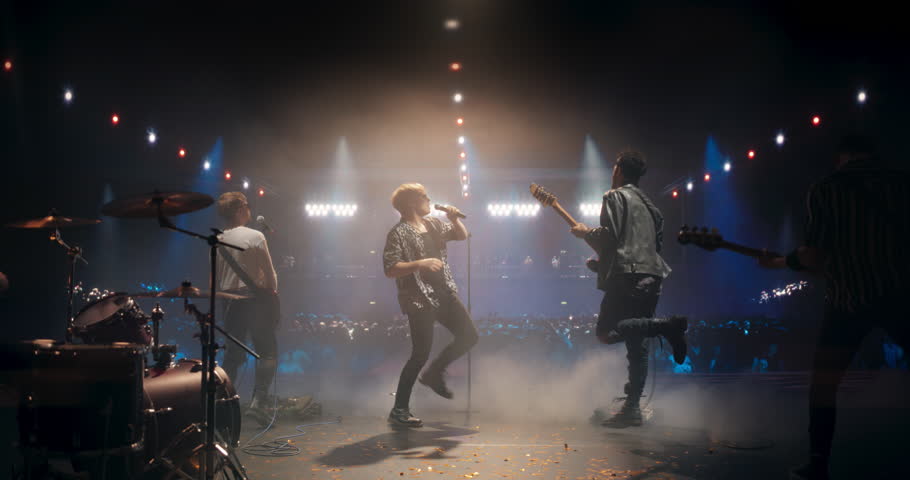 Talented Rock Band Performing a Live Set on an Indoors Stage with Fire Pyrotechnic Effects. Young Musicians Playing a Concert at a Festival, Singing Hard Rock Songs at an Indie Event. Back View