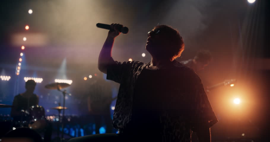 Portrait of a Stylish Lead Singer Performing at a Rock Concert Live on Stage. Talented Musician Bringing His Unique Attitude, Playing Energetic Rock Hits. Young Band Playing For the Crowd