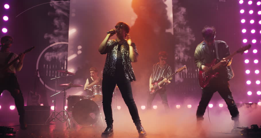 Band Playing Hit Songs on Electric Guitars and Drums. Young Rock Musicians Performing a Live Concert, Dancing, Having Fun, Entertaining a Crowd of Rock Music Fans at an Alternative Festival