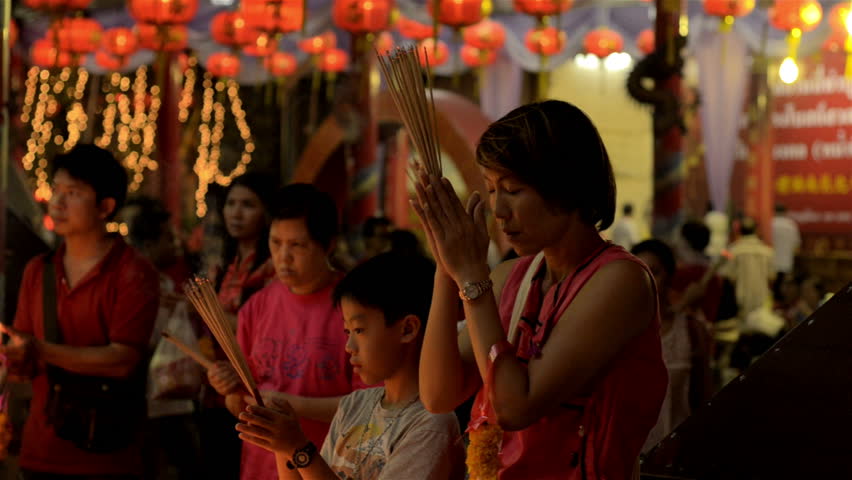 BANGKOK, THAILAND  - FEBRUARY 9, 2013: Mother teaching her son to pray at Wat