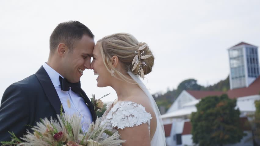 Bride and groom laugh together in front of beautiful building