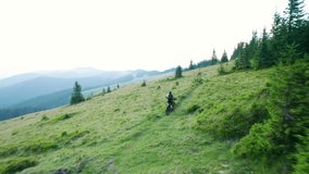 Cyclist man riding electric mountain bike outdoors. Aerial view of male tourist biking along grassy trail in the mountains, wearing helmet and backpack. Concept of sport, active leisure and nature. - Powered by Shutterstock - Get 15% off with code: PIKWIZARD15