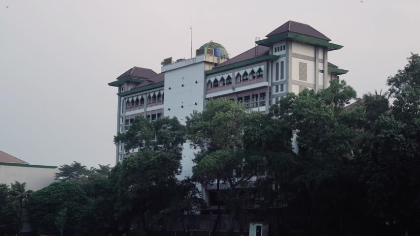 side view of the university building surrounded by trees and the sky as an empty background.