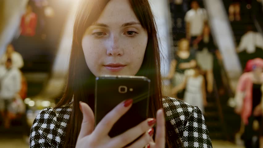 Focused Woman on her Smart Phone amidst the Urban Chaos