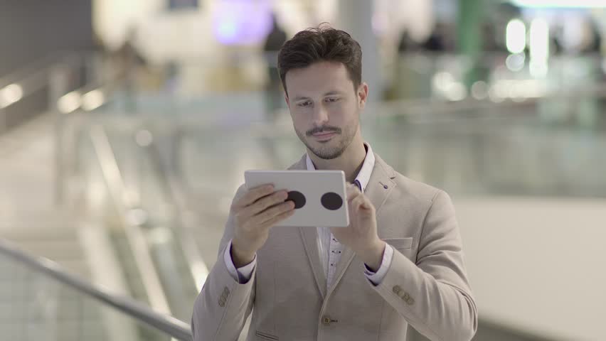 Man is Shown Using a Tablet Screen in the Midst of a Busy Street
