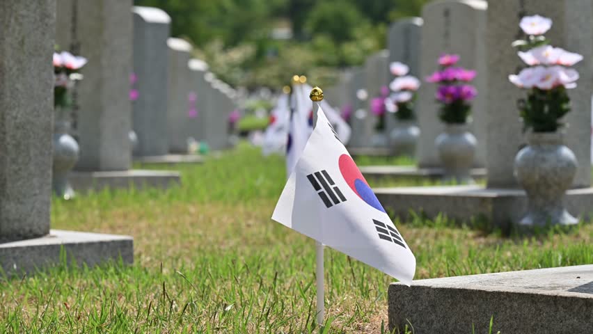 Summer scenery of Seoul National Cemetery with tombstones and Korean flag on green lawn