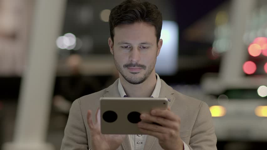 Man is Shown Using a Tablet Screen in the Midst of a Busy Street