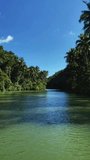 Panoramic vertical video spanning left to right of the picturesque Loboc River in Bohol, Philippines, showcasing its serene waters and lush surrounding greenery