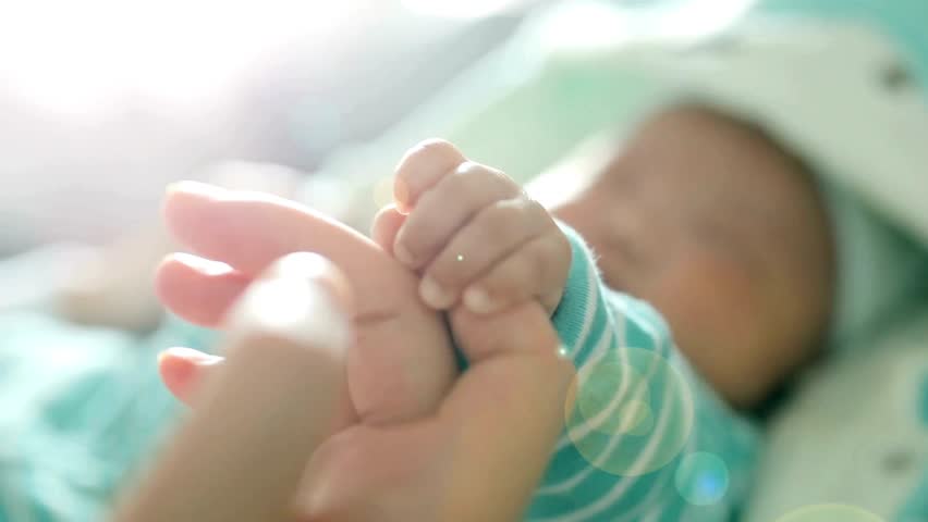 Small Newborn baby holding mother's finger. Motherhood concept. baby's hand has firm grip on the parent's finger. An infant gripping mother finger.