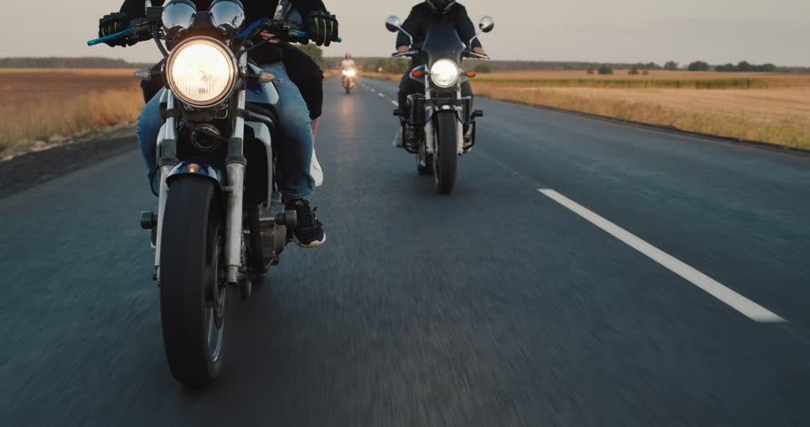 Bikers drive on the highway, close-up steering wheel. Other motorcyclists can be seen in the background.