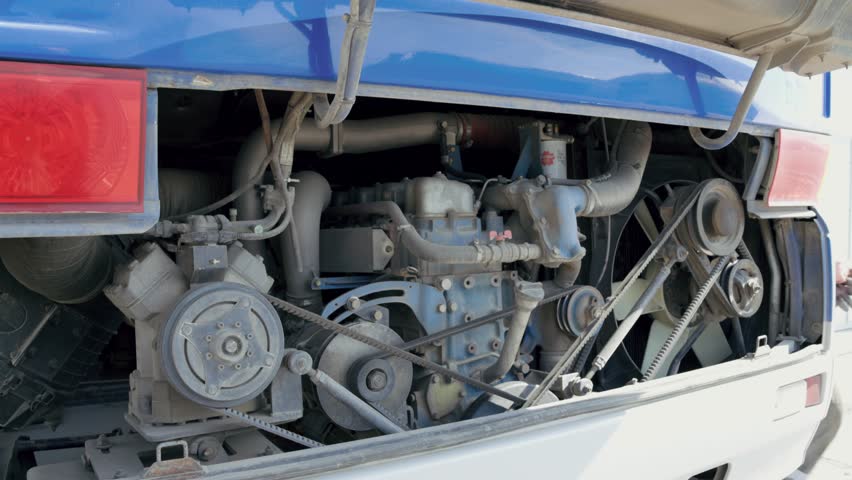 A mechanic in blue is fixing a bus engine, focusing on mechanical parts under the vehicle. Video 4k.