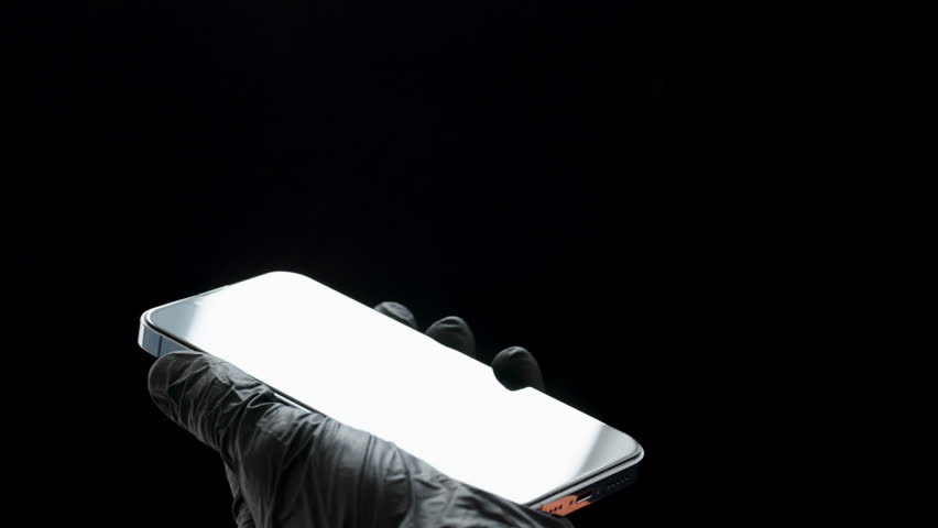 Wiping a Smartphone Screen with an Orange Cloth, a Person in Black Gloves. Repair Shop Concept.
