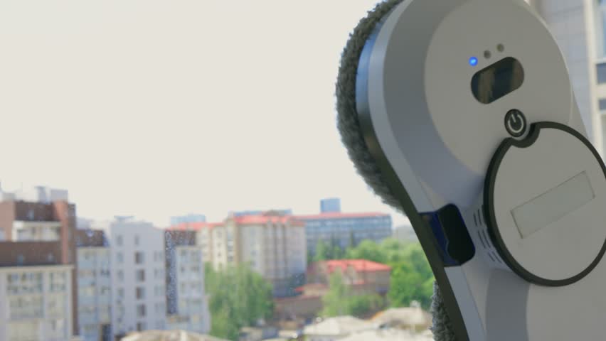 A robotic white Automotive tire is cleaning a glass window