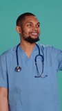 Vertical video Male nurse using mobile phone to take selfies during hospital job shift break. Healthcare worker using smartphone to take pictures of himself, isolated over studio background, camera B