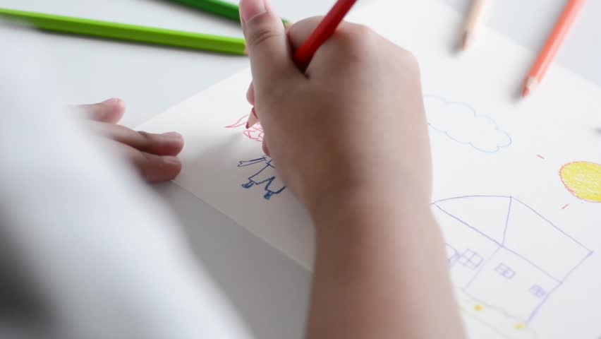 Close up children's hands draw and paint on white paper with colorful pencils.	