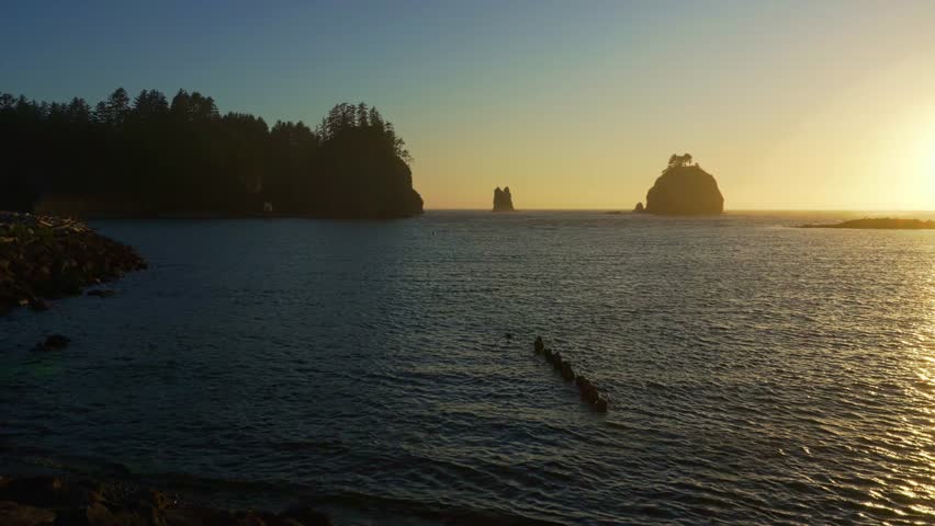 Pan right of La Push Beach at sunset with silhouetted sea stacks in the Olympic National Park area. 4K UHD video.