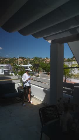 A woman relaxing on a sunny balcony with a VR headset, embracing modern technology