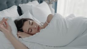 A woman peacefully sleeping in bed with white sheets. The image captures a serene and restful moment in a cozy bedroom setting. Ideal for concepts of relaxation, sleep, and comfort. - Powered by Shutterstock - Get 15% off with code: PIKWIZARD15
