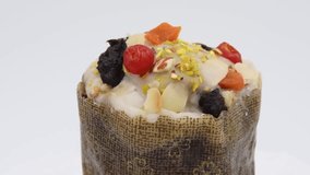 Close-up view of tasty Easter cake (or russian Kulich) with white icing, slices of nuts and dried fruits turning against gray background. Real time video. Soft focus. Traditional holiday food theme.