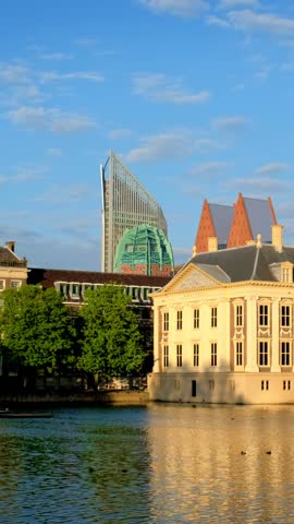 View of the Binnenhof House of Parliament and the Hofvijver lake with downtown skyscrapers in background. The Hague, Netherlands. Camera pan
