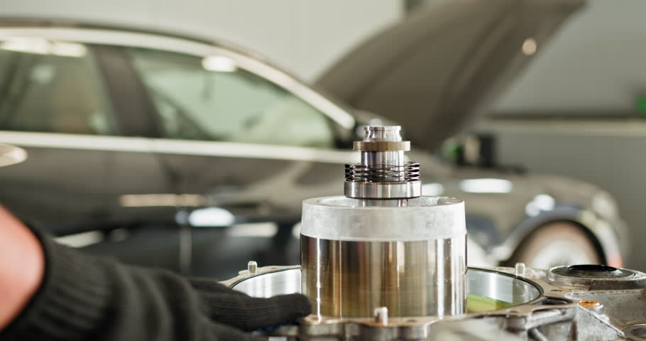 Close-up of auto mechanic's hands repairing an electric car engine in a workshop. Hands in gloves working on motor components. Auto Mechanic Repairing Electric Car Engine in Workshop