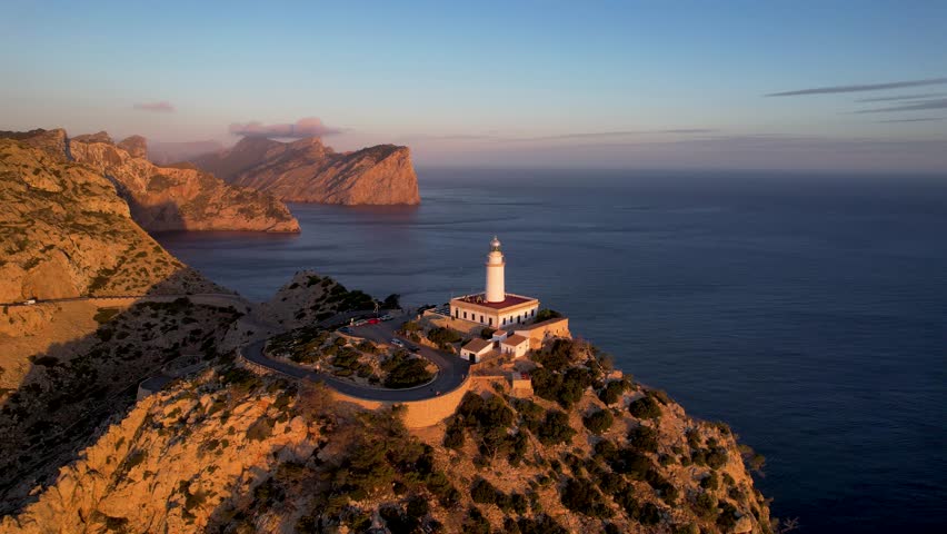 4K Aerial Drone video of fiery red sunrise from the wide sea horizon over the picturesque lighthouse on the cliffs edge, Far of Cap de Formentor, Mallorca, Spain