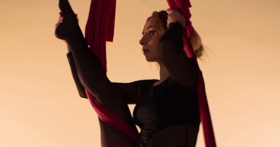 Aerial gymnast portrait in studio with beautiful diffused lighting and defocus. The girl is a gymnast on acrobatic canvases.