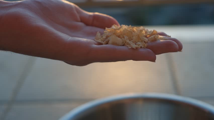 A man rubbing dry petals or herbs in his hands, close-up