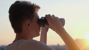 Young man looking through binoculars at sunset, close-up - Powered by Shutterstock - Get 15% off with code: PIKWIZARD15