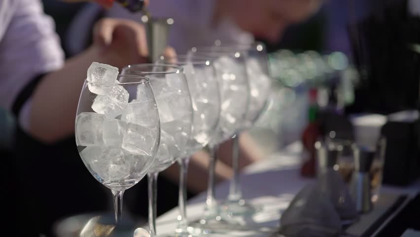 The waiter or bartender mixing cocktail in glasses. Welcome drink at a celebration or wedding reception in a restaurant or vacation bar. Alcoholic Beverage. Drinking straw.