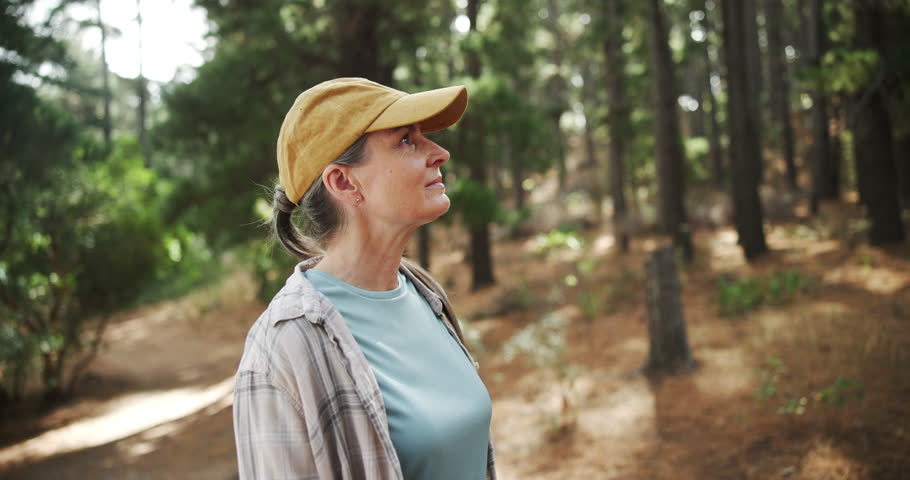 Hiking, thinking or mature woman in nature, woods or wilderness for trekking or outdoor adventure. Smile, relax or hiker walking in park, forest or Norway for exercise or wellness on holiday vacation