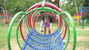 Asian little girl is playing on a colorful playground slide. The slide is made of metal and has a blue, red, and green design. The girl is climbing up the slide and he is enjoying herself - Powered by Shutterstock - Get 15% off with code: PIKWIZARD15