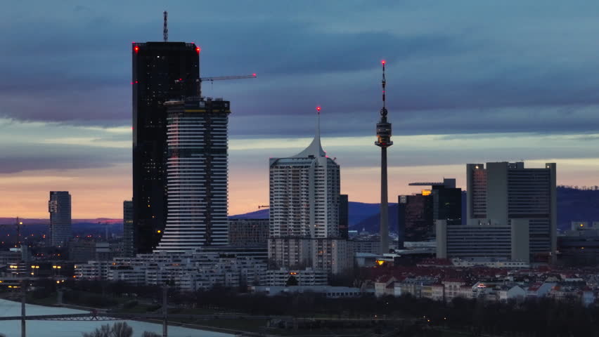 Aerial view cityscape sunset in Vienna Austria. Beautiful city skyline with high-rise TV towers transition from day to night, modern architecture of the business district of the capital. 