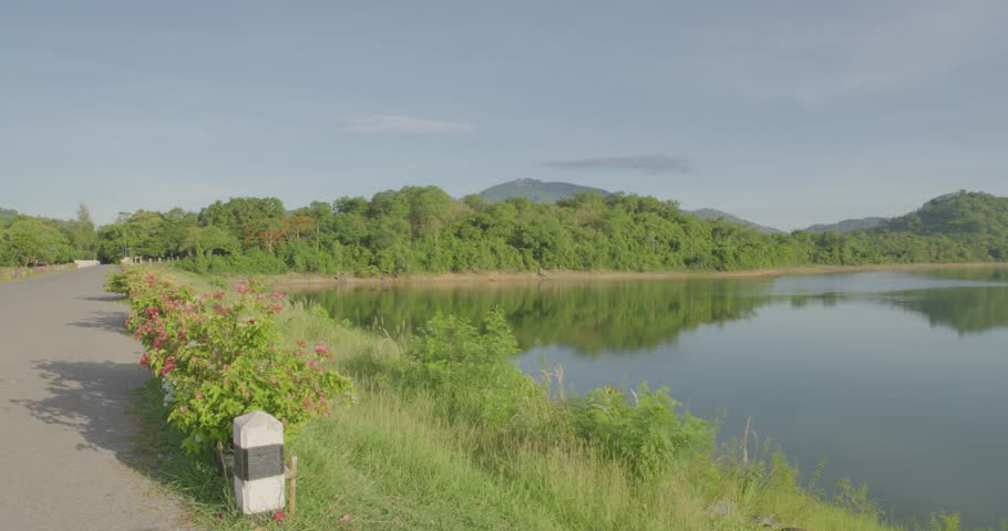 Huai Prue reservoir in Nakhon Nayok province, Thailand. Landscape scenic view of mountains and hillside in morning sunrise with natural lens flare.