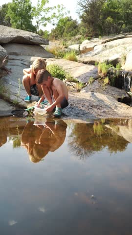 Boys with a fishing net in a river in summer