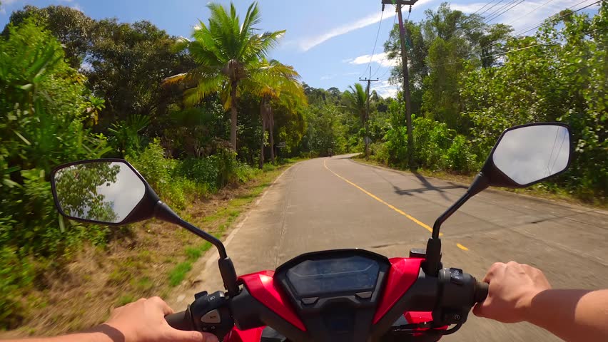 Riding a scooter on a tropical island in Thailand. Rider's point of view