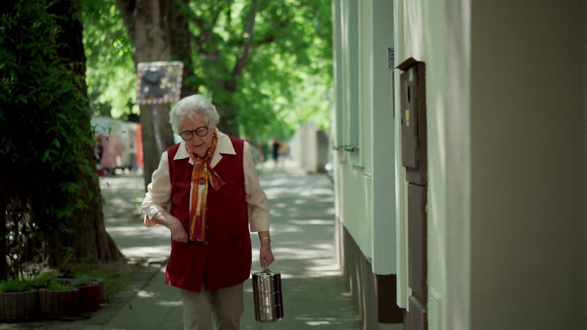 Senior woman with getting home with food in lunchbox from local restaurant.