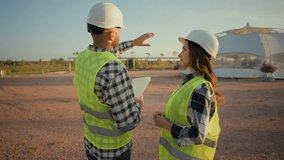 Couple Caucasian technician workers workwear talking. Man inspector hold checklist show plan gesturing woman ecology engineer discussing talk building project details outdoors countryside construction - Powered by Shutterstock - Get 15% off with code: PIKWIZARD15