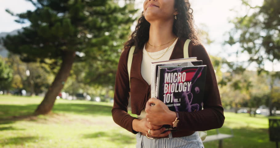 Happy woman, student and walking with science books in nature for learning, education or studying at outdoor park. Young female person with smile or microbiology textbooks for reading or research