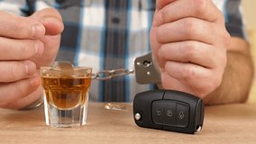 A man in handcuffs drinks a glass of alcohol and takes the car keys. The concept of driving under the influence of alcohol. Slow motion - Powered by Shutterstock - Get 15% off with code: PIKWIZARD15