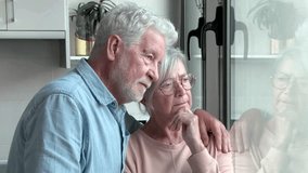 Sad and distressed white-haired retired elderly couple looking out the window, senior man comforts his wife with health or financial problems, senior woman ready to cry - Powered by Shutterstock - Get 15% off with code: PIKWIZARD15