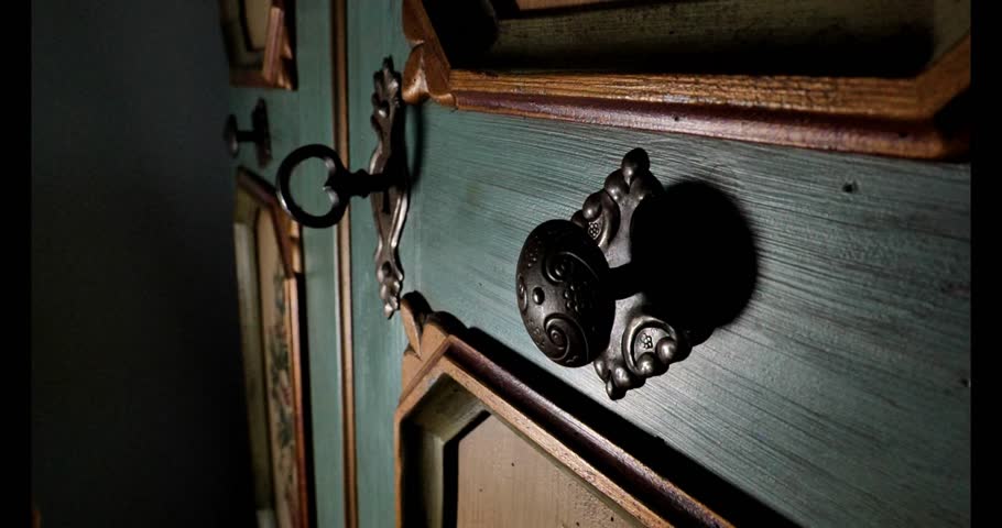 Mysterious and tense mood.Enigmatic Wooden Door with Key.hand opens a wooden antique door with an old key to reveal the secrets of a dark room. atmosphere of mysticism. 4k footage