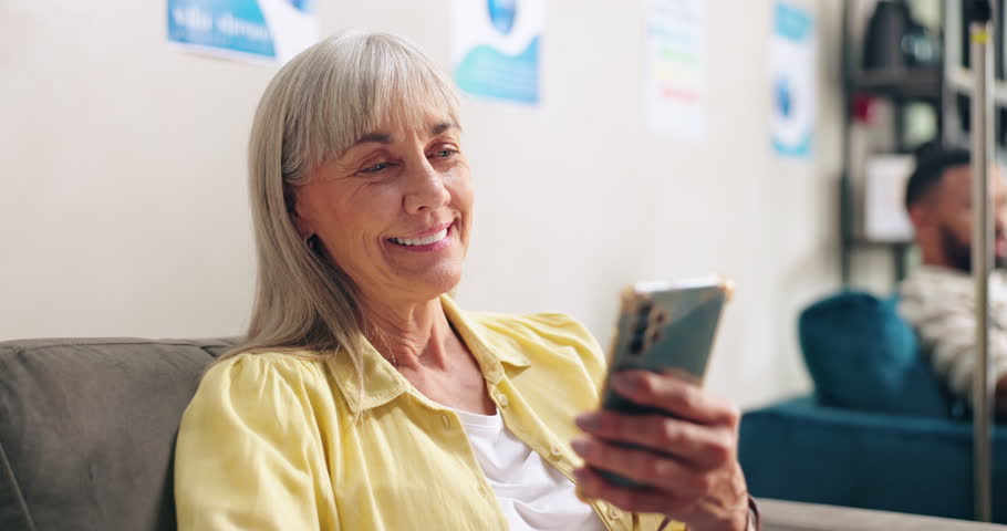 Hospital, phone and senior happy woman in chemotherapy for cancer treatment, medication and IV drip of medicine. Healthcare, clinic and person on smartphone for social media, website and funny joke