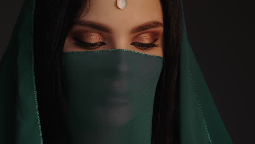 Beautiful sensual woman in traditional costume. Romantic portrait of young girl with perfect bright makeup wearing clothes standing indoors against dark background. Fine art 4K UHD footage