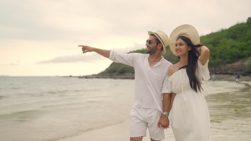 4K Happy Caucasian couple enjoy and fun outdoor lifestyle travel nature at the sea on summer beach holiday vacation. Man and woman walking and playing together at tropical island beach at sunset. 