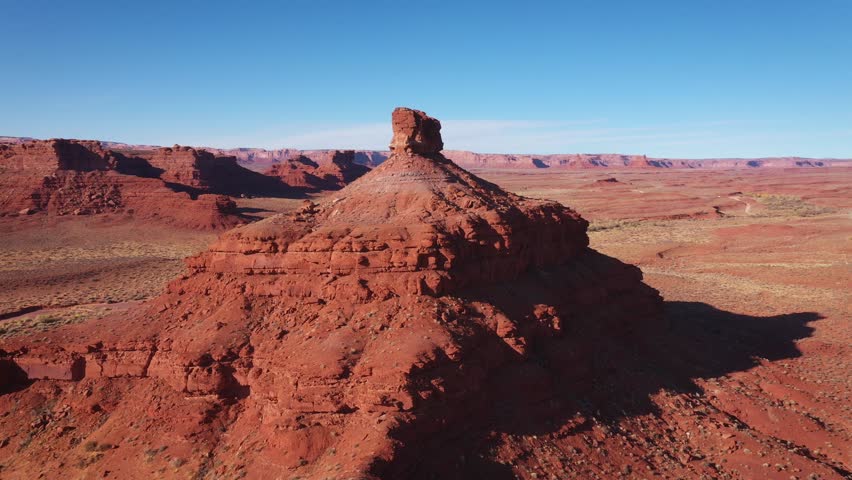 Traveling western Usa on motorcycles and cars, vehicles travel along highway through hot desert. Rocky remnants similar to Grand Canyon in desert of Arizona or Utah. Drone flight around rock tower