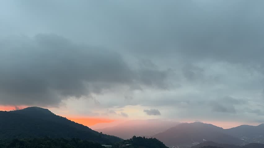 Gray clouds were moving quickly over the mountains and the sun was shining.