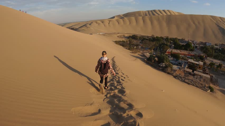 Girl walking on sand dune  at Huacachina desert. Slow motion steadicam footage.